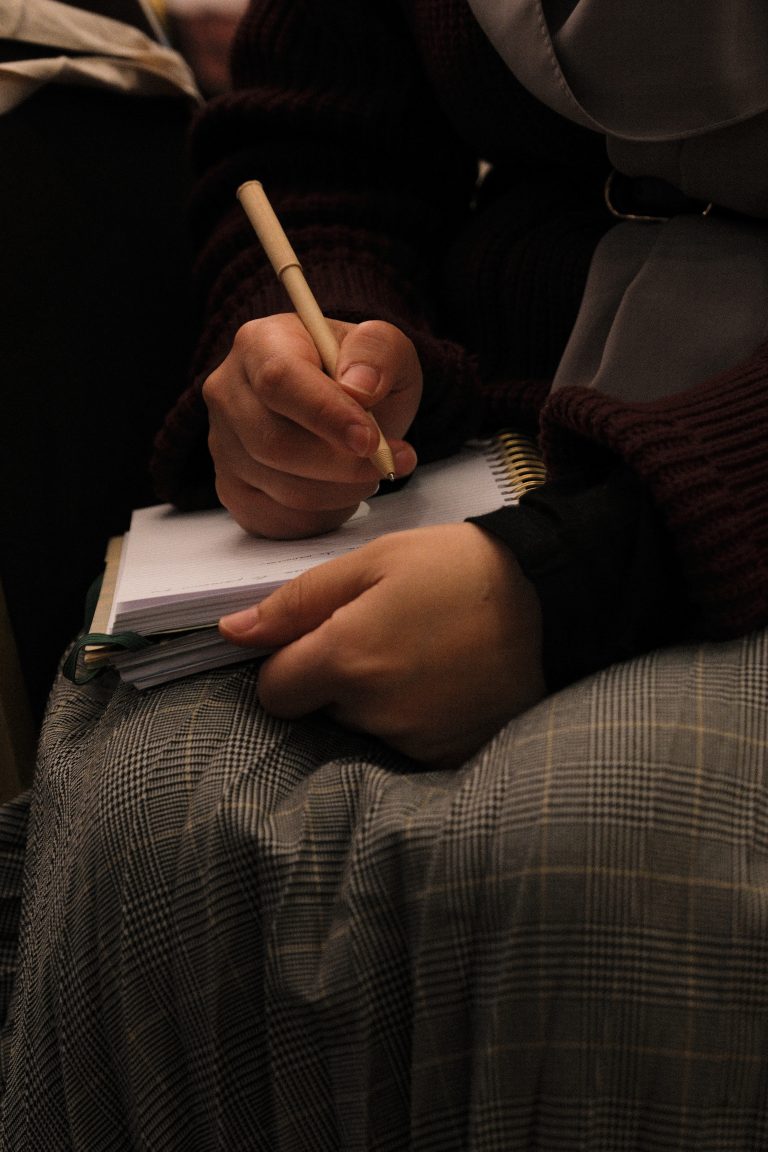 Une participante prend des notes dans son carnet pendant un enseignement
